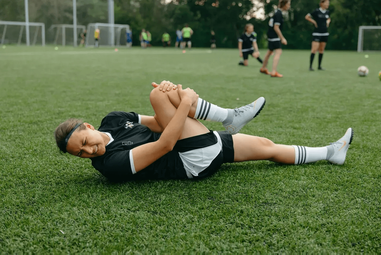 Young athlete holding an injured knee during sports practice