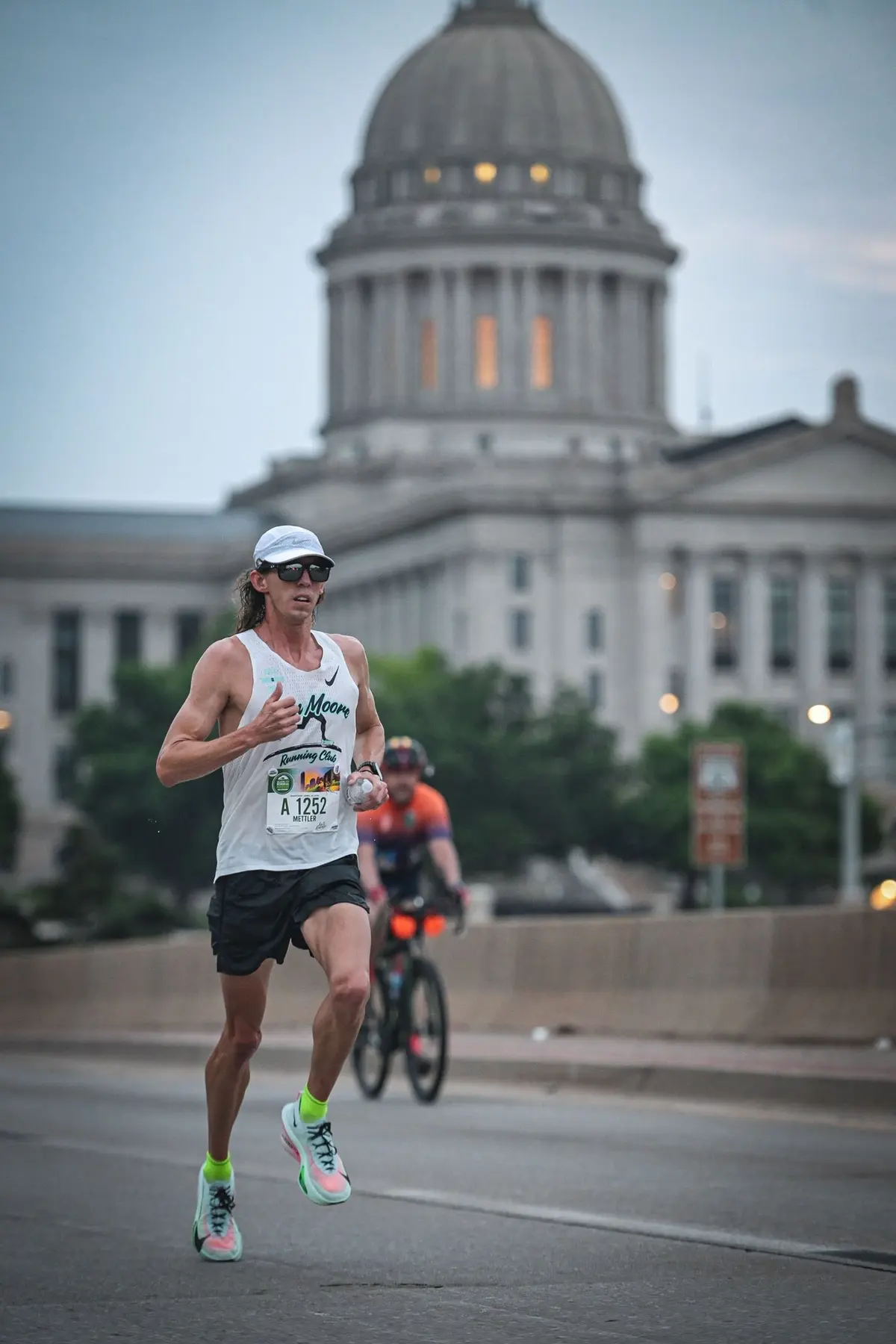 Adult athlete running with the Oklahoma State Capitol in the background